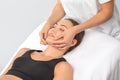 Masseur makes a relaxing massage on the face, neck, shoulders and collarbones of a young beautiful woman in a spa. Cosmetology and