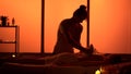 Masseur, massage specialist giving a massage to his patient using herbal bags. Silhouettes in the massaging room, spa