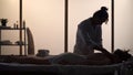 Masseur, massage specialist giving neck massage to his patient. Silhouettes of a woman and a man in the massaging room Royalty Free Stock Photo