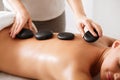 Masseur placing stones on woman`s back, closeup