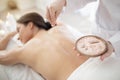 Masseuse applying mineral salt body scrub on back of young woman Royalty Free Stock Photo