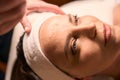 Experienced massotherapist preparing adult woman for face massage