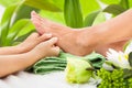 Masseuse massaging woman's foot against leaves