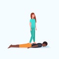 Masseuse in uniform standing on patient`s back doing healing treatment african american guy having massage manual