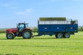 Massey Ferguson tractor pulling a trailer in grass field Royalty Free Stock Photo