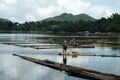 Massive body boatman paddle bamboo raft boat across mountain lake.