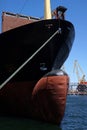 The massive bow of a large ship, with the radar dome above the surface of the water with crane, at the seaport. vertical. Royalty Free Stock Photo