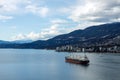 A massive cargo ship navigates under Lions Gate Bridge in Burrard Inlet, with the West Vancouver skyline in the background Royalty Free Stock Photo