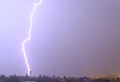 Massive cloud to ground lightning bolts hitting the horizon of city lights