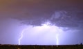 Massive cloud to ground lightning bolts hitting the horizon of city lights