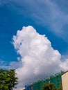 Massive cloud - towering cumulus - forming over building under construction with scaffolds and safety net Royalty Free Stock Photo