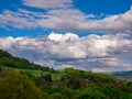 Massive clouds - Cumulonimbus - forming in the blue sky over hilly landscape Royalty Free Stock Photo