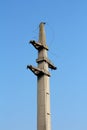 Massive concrete electrical utility pole with cut electrical wires hanging from top