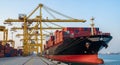 Massive container ship docked at a port with yellow cranes loading cargo under a clear sky cargo ship Royalty Free Stock Photo