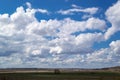 Massive cumulus white clouds in a blue sky over a green plain. Royalty Free Stock Photo