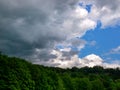 Massive dark storm clouds coming from right over a wooded hill Royalty Free Stock Photo