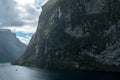 Massive geiranger fjord in norway seen from a cruise ship with light shining through the clouds and waterfall