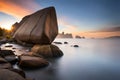 A massive granite boulder precariously balanced on the edge of a rocky cliff, defying gravity