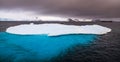 Massive iceberg with blue uderwater part and cruise ship in back