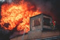 Massive large blaze fire in the city, brick factory building on fire, hell major fire explosion flame blast, with firefighters