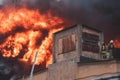 Massive large blaze fire in the city, brick factory building on fire, hell major fire explosion flame blast, with firefighters