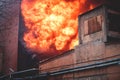 Massive large blaze fire in the city, brick factory building on fire, hell major fire explosion flame blast, with firefighters