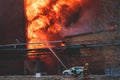 Massive large blaze fire in the city, brick factory building on fire, hell major fire explosion flame blast, with firefighters