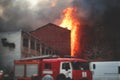 Massive large blaze fire in the city, brick factory building on fire, hell major fire explosion flame blast, with firefighters