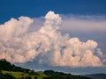 Massive rain clouds - Cumulonimbus - forming in the blue sky over hilly landscape Royalty Free Stock Photo