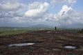 A massive rock surface, dramatic sky and a boy standing edge of the mountain