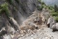 massive rockslide from cliff, with jagged rock fragments and dust