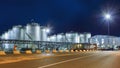 Massive silos at illuminated petrochemical production plant at nighttime, Port of Antwerp, Belgium.