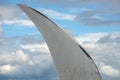 Massive unmarked airplane folding wingtips in blue sky with clouds background