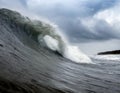 A massive wave crashes in the water on a cloudy day, stirred up by the wind Royalty Free Stock Photo