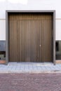 Massive wooden entrance door to modern white house with paving footpath in the city.