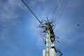 A mast with a network of many different power cables is photographed from below against the blue sky with clouds Royalty Free Stock Photo