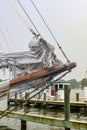 The mast of a retro sailboat with a working fishing and crabbing boat in the backgrount.