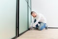 master adjusts sliding doors of wardrobe made of metal and glass. Royalty Free Stock Photo