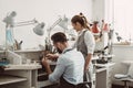 Master and apprentice. Young male assistant and female jeweler are working together at jewelry making workshop. Royalty Free Stock Photo