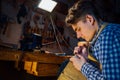 Master artisan luthier working on the creation of a violin. painstaking detailed work on wood.