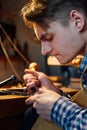 Master artisan luthier working on the creation of a violin. painstaking detailed work on wood.