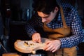 Master artisan luthier working on the creation of a violin. painstaking detailed work on wood.