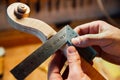 Master artisan luthier working on creation of a violin scroll. detailed work on wood with tools.