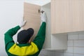 The master of the assembly of kitchen furniture, installs the facades of the doors on the top drawers, there is a place for the Royalty Free Stock Photo