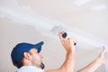 The master attaches the reinforcing tape to the joint of drywall sheets with a spatula and putty