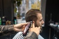 Master in barbershop makes men's haircutting with hair clipper Royalty Free Stock Photo