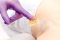 Master beautician removes hair from female underarm with sugar paste, white color. Sugaring beauty concept