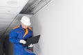 A master in a blue uniform, laid the wiring for the Wi-Fi router in a hidden false ceiling system and verifies the correct