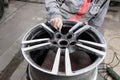 Master body repair man is working on preparing the surface of the aluminum wheel of the car for subsequent painting in the