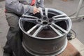 Master body repair man is working on preparing the surface of the aluminum wheel of the car for subsequent painting in the